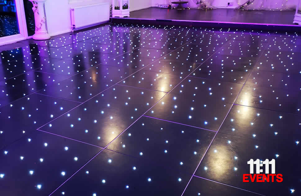 Black starlit LED dance floor for a wedding event with pink uplighters