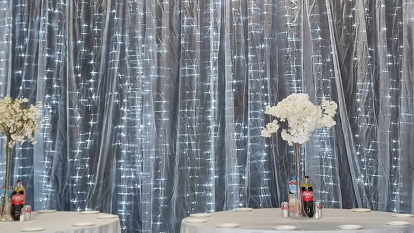 Cool white fairy light curtain backdrop with LEDs behind voile