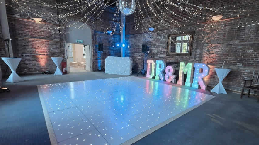 A complete setup with white starlit dance floor, mirror ball, fairy lights, DJ, mood lights and DR&MR light up letters at Highcliffe Castle