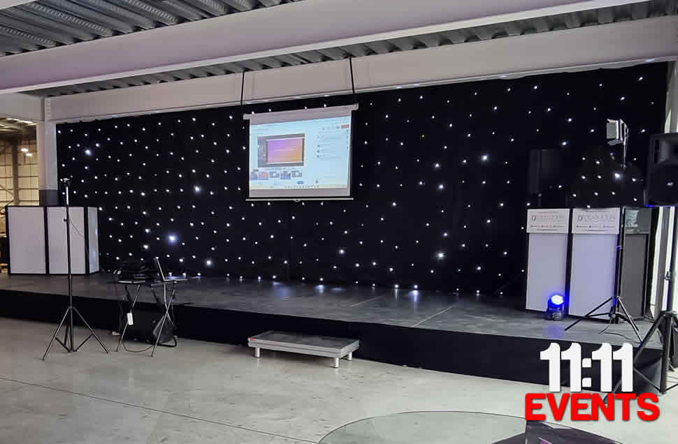Wide stage for product launch with black starcloth, sound system and microphone Southampton